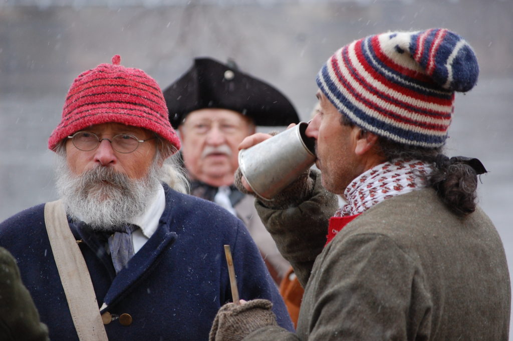 Man in colonial garb drinking from a pewter cup